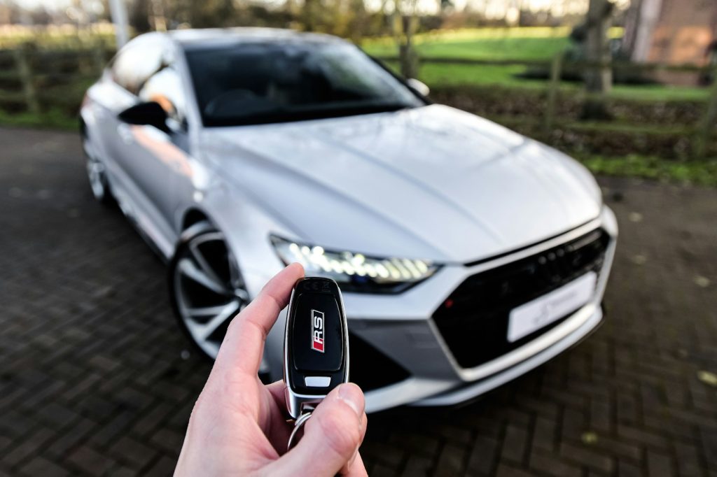 Person holding a car key in front of a silver car